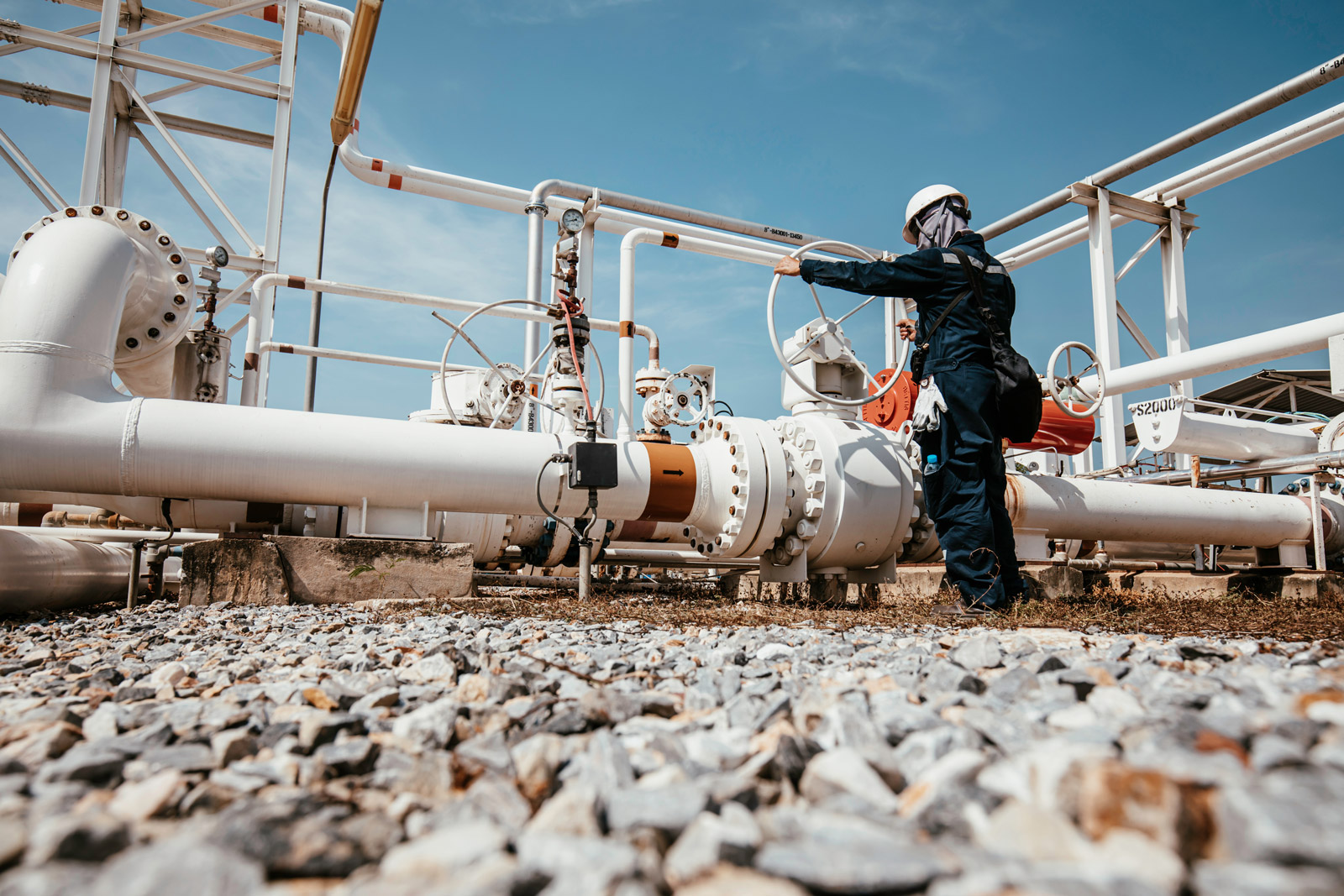 oil and gas pipe network with worker inspecting