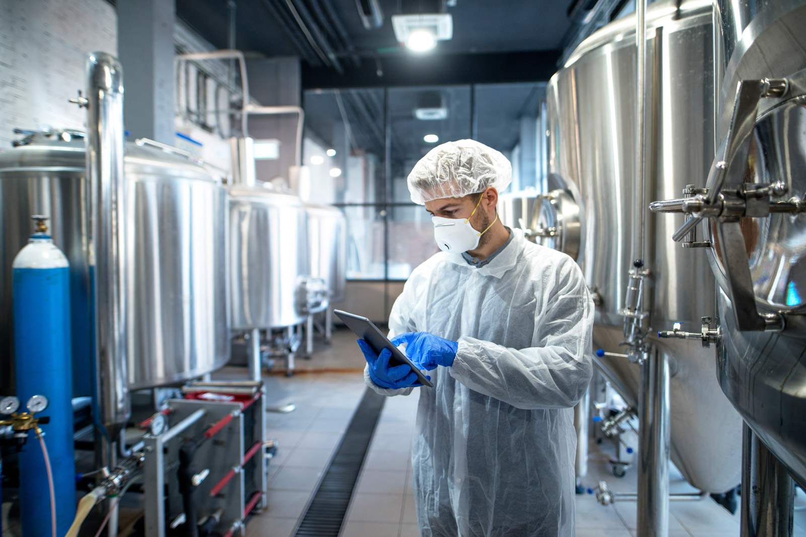 man in lab coat and face mask surrounded by chemical drums